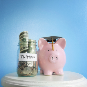 Glass jar with tuition written on it and a piggy bank with a graduation hat on.