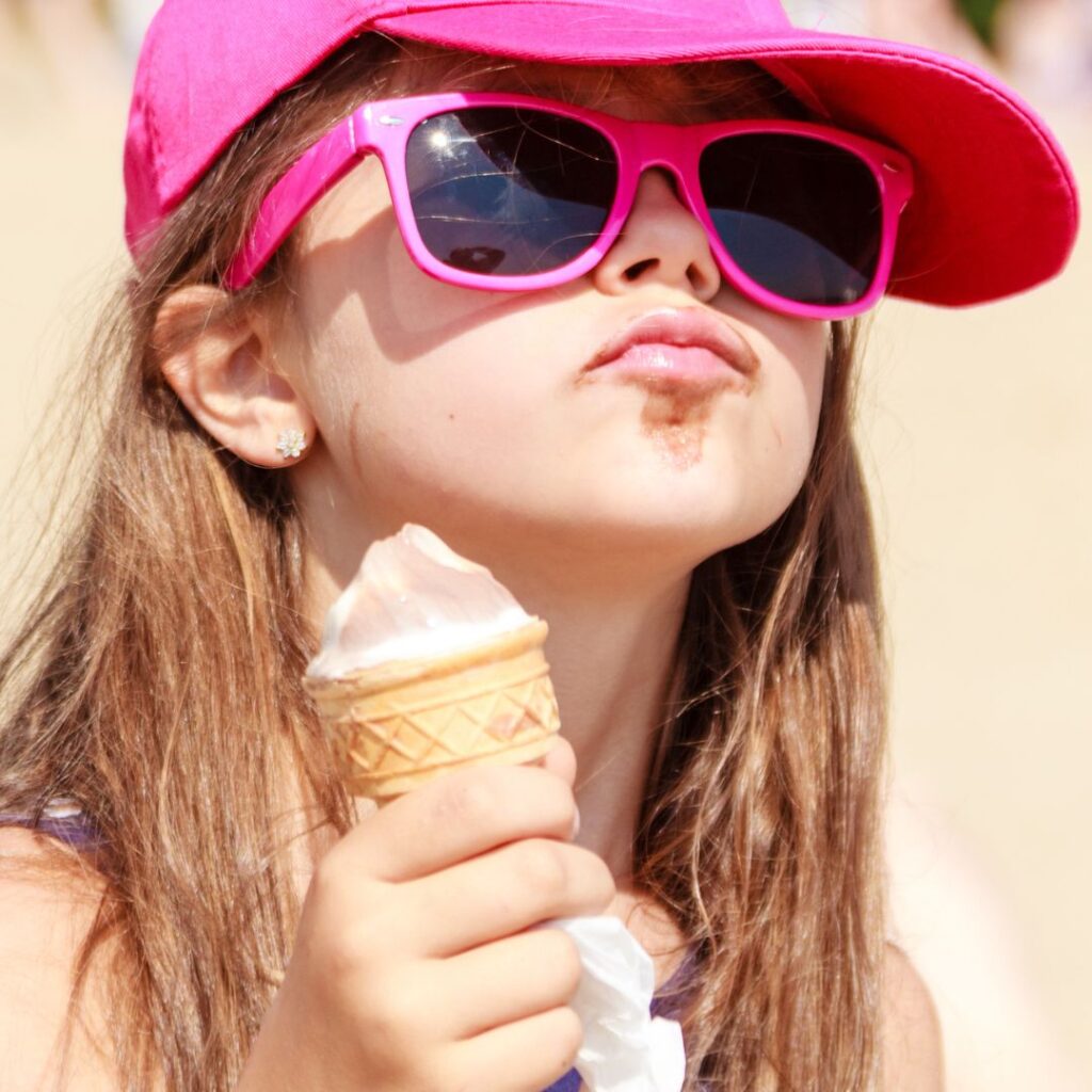 Little girl with hat, sunglasses and ice cream cone.