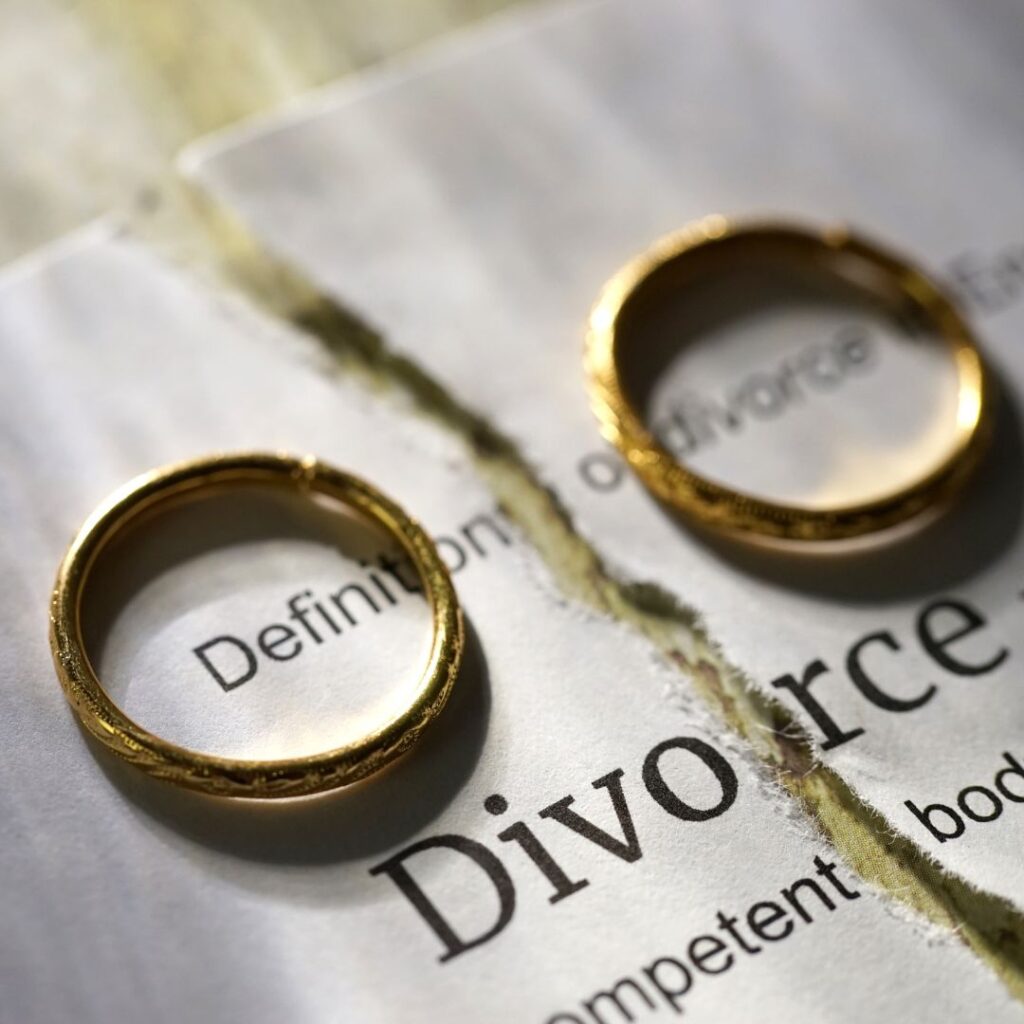 Torn divorce paper with wedding rings on top.