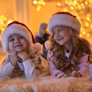 Two children laying on floor in front of holiday lights