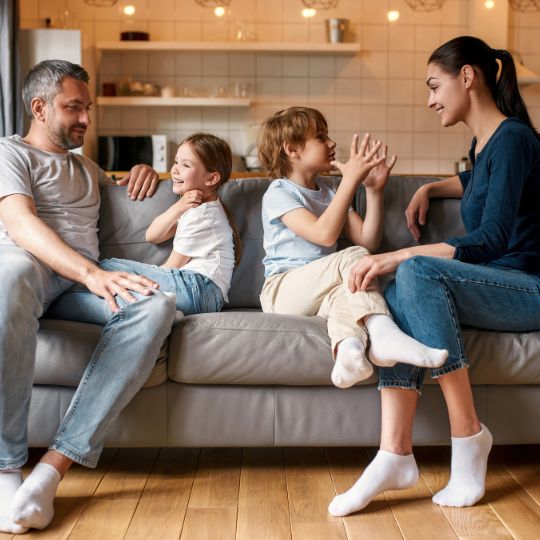 Parents and children sitting on the couch talking.